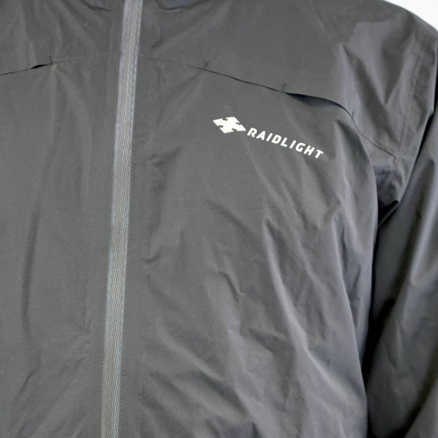 Raidlight Top Extreme Ultra MP+ Herren in Schwarz – Detail des reflektierenden Mittelreißverschlusses und Logos