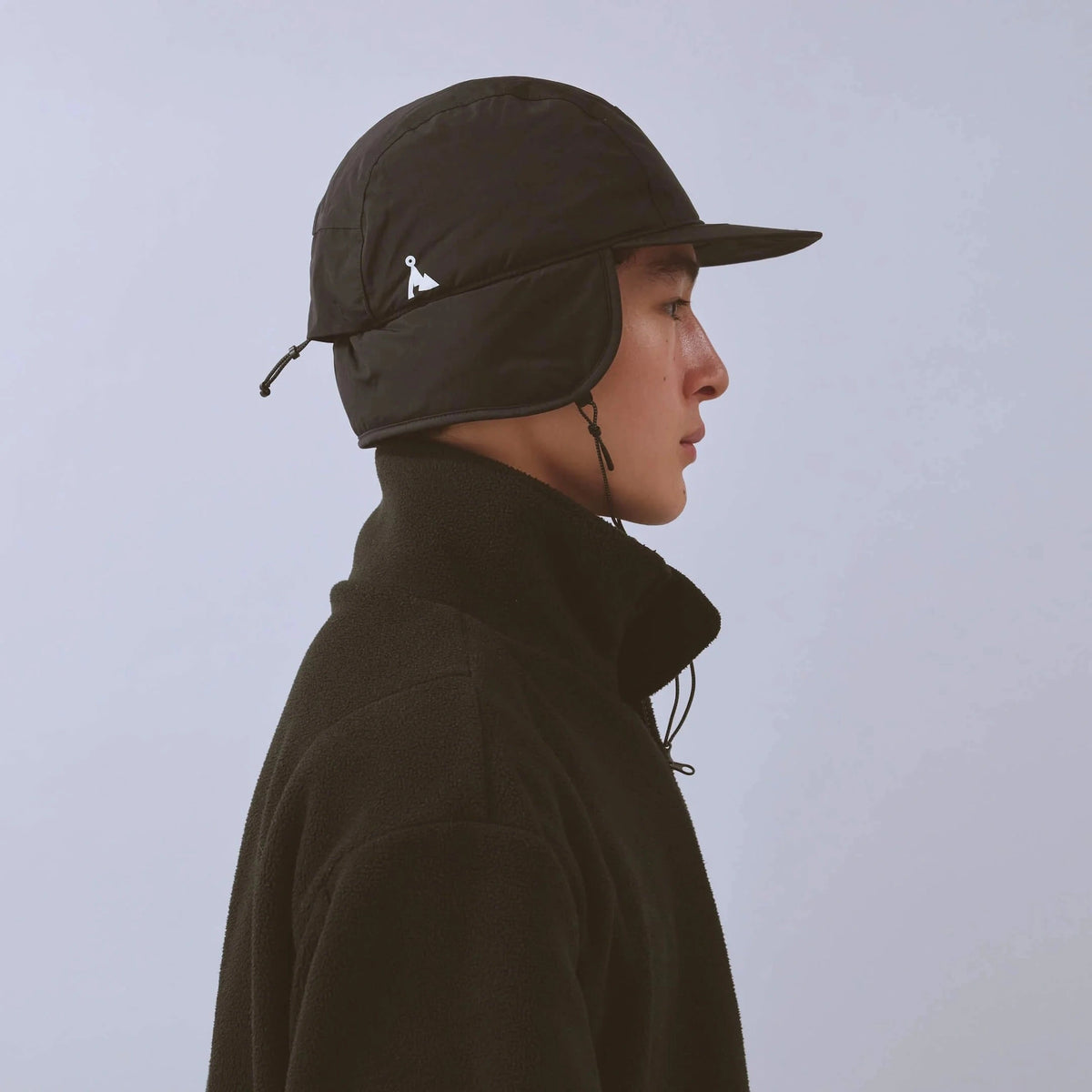 Vaga Padded Hiker Cap in Schwarz – getragen, Seitenansicht mit heruntergeklappten Ohrenklappen