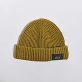 Våga Midweight Beanie in Moosgrün – flach liegend, Vorderseite mit Label