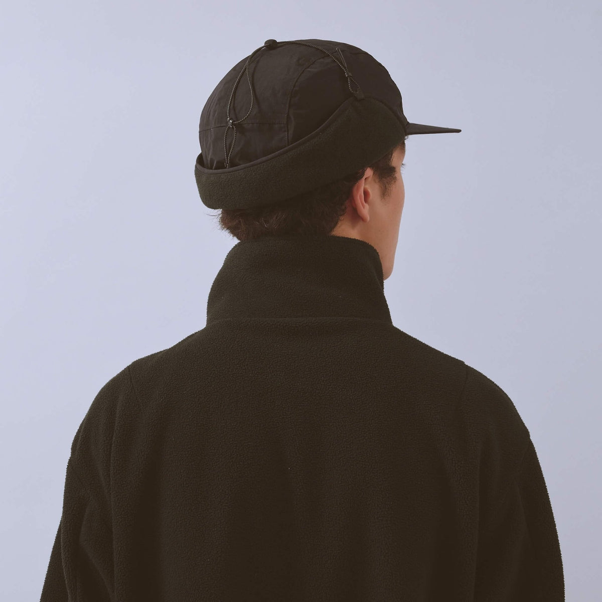 Vaga Padded Hiker Cap in Schwarz – getragen, Rückansicht mit hochgeklappten Ohrenklappen