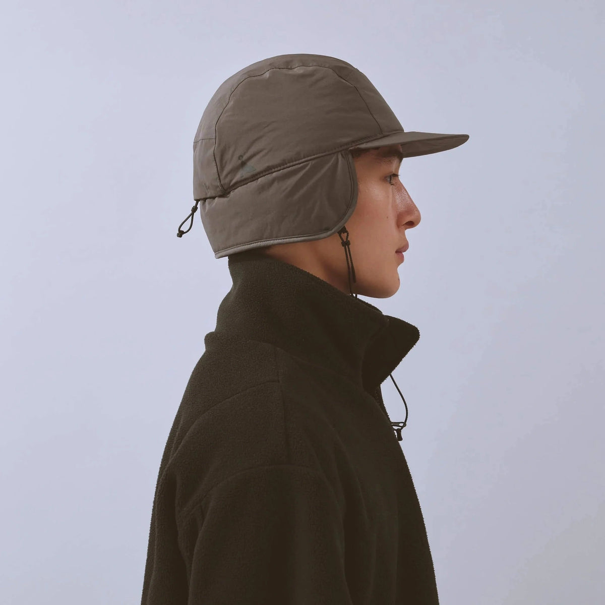 Vaga Padded Hiker Cap in Grau – getragen, Seitenansicht mit heruntergeklappten Ohrenklappen